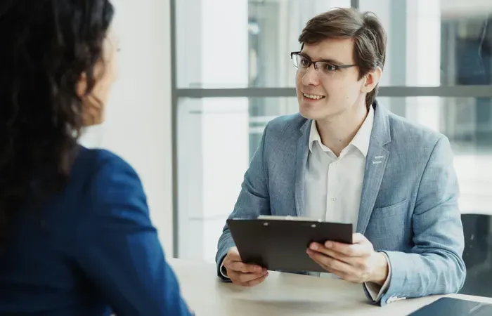 Smiling professional meeting a client with a clipboard in a bright office, discussing services on Local Biz List